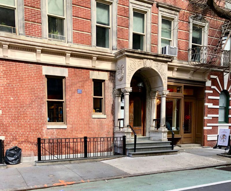 A current-day photo of the stairwell and iron rail that leads to the former basement entrance of the Snake Pit, located to the left of the apartment building entry.(NYC LGBT historic Sites Project)