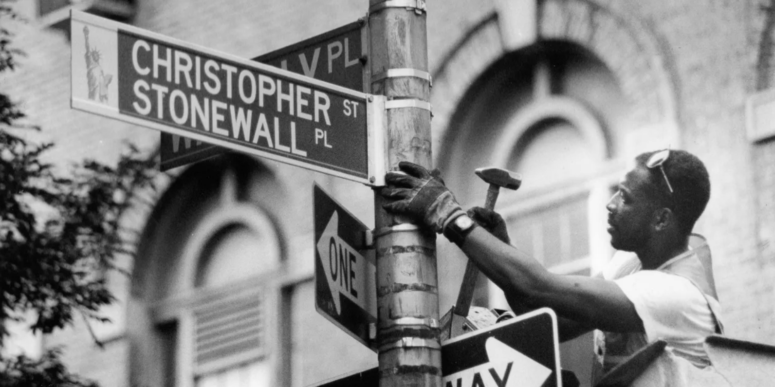 Darryl Beckles, a traffic device worker in New York City, changes the street sign on Christopher Street in Greenwich Village